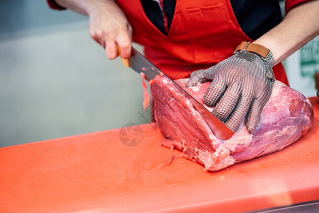 女屠夫肉店用金属安全网手套切鲜肉女人肉店用金属安全网手套切鲜肉背景图片