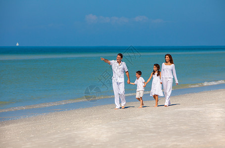 幸福的家庭,母亲,父亲两个孩子,儿子女儿,牵着手走,阳光明媚的沙滩上玩得很开心图片