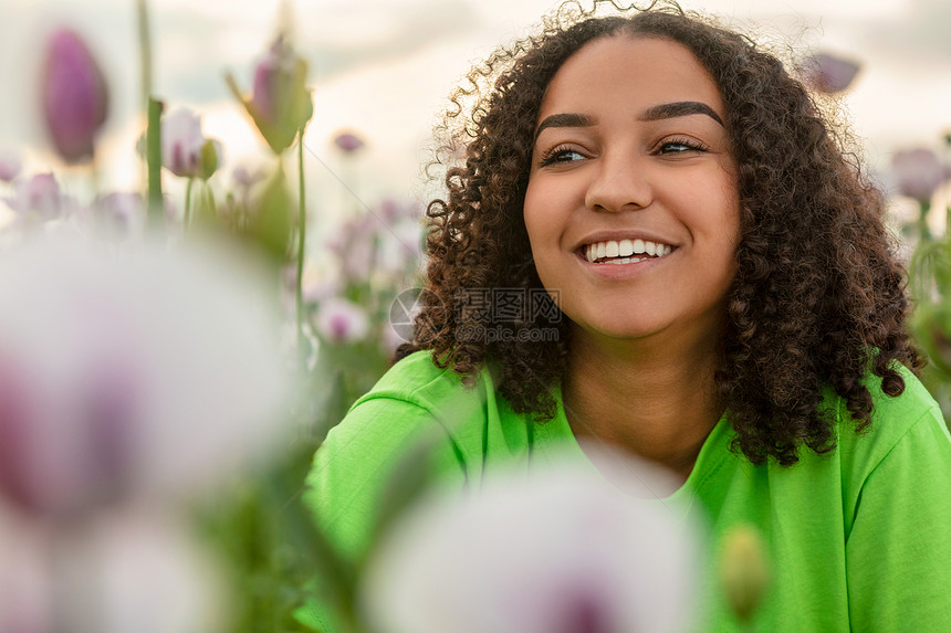 混合种族美丽的非裔美国混血女孩,十几岁的女青年,穿着绿色的t恤,粉红色的花朵,花,日落或日出,微笑与完美的白色牙齿图片