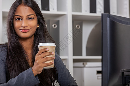 位美丽的年轻亚洲印度妇女或女商人办公室用电脑喝外卖茶或咖啡的肖像图片