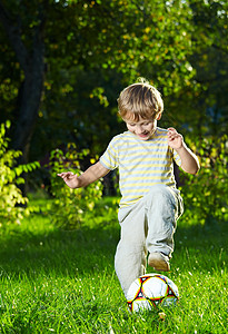 小男孩夏天的花园里踢足球图片