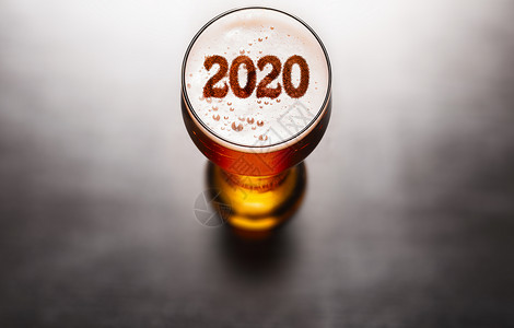 新年啤酒黑色桌子上啤酒玻璃泡沫上的2020符号,上面看新年2020啤酒图片