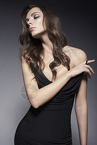 时尚工作室美丽年轻女人的肖像感的女士,卷发,黑色连衣裙图片