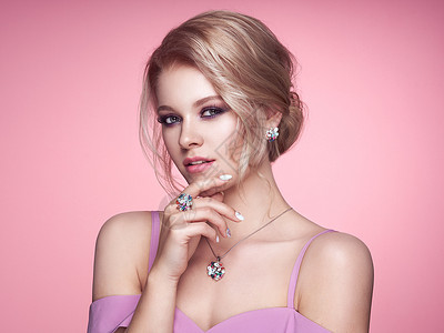 用珠宝描绘美丽的金发女人模特女孩用珍珠指甲修剪指甲优雅的发型宝石银美容时尚配饰完美的化妆粉红色的背景背景图片