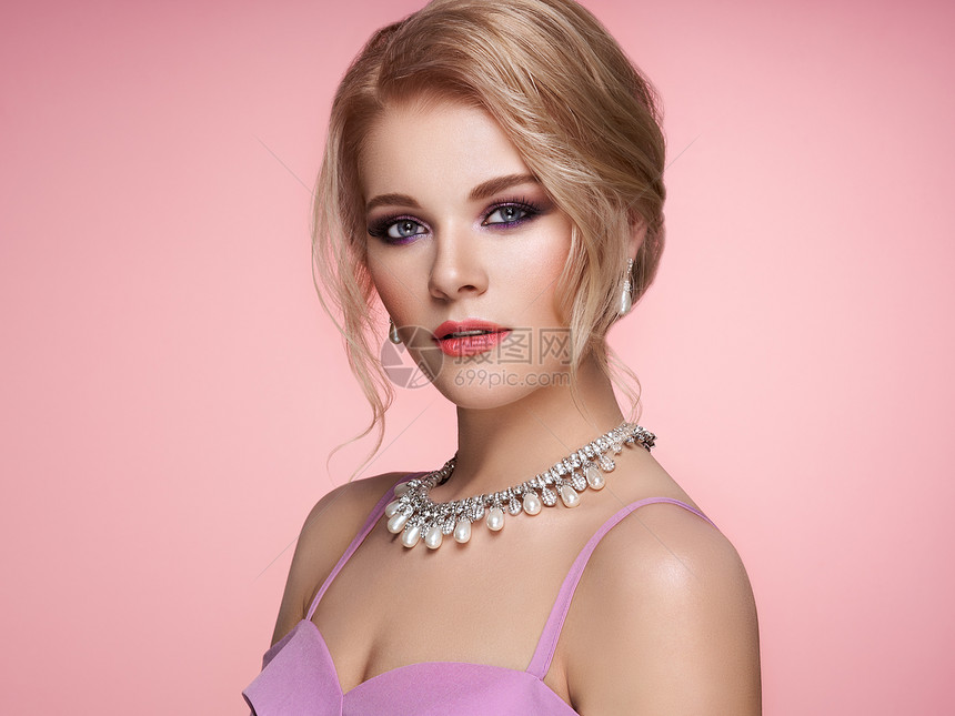 用珠宝描绘美丽的金发女人模特女孩用珍珠指甲修剪指甲优雅的发型美容时尚配饰完美的化妆粉红色的背景图片