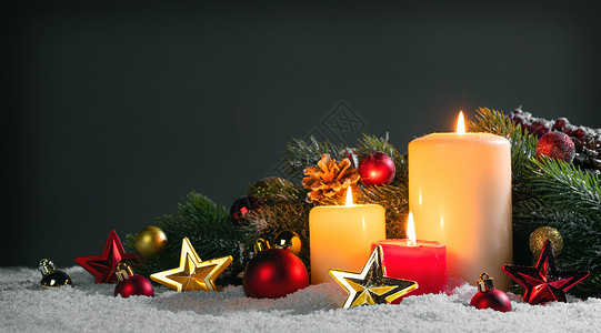 发光星星装饰圣诞蜡烛与传统的装饰星星,红宝贝,松果绿色的树枝雪上带有装饰的圣诞蜡烛背景