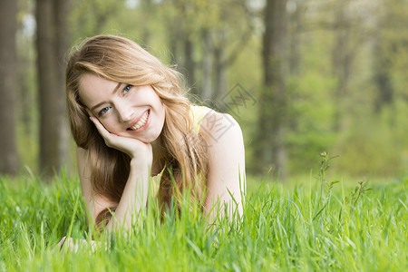 金亮的女孩躺春天公园的草地上微笑躺草地上的女孩图片
