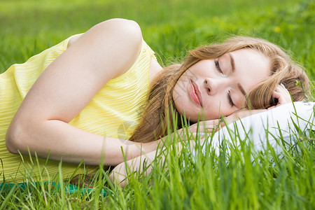 休息放松的女人睡大自然的草地背景上的枕头上休息放松的图片