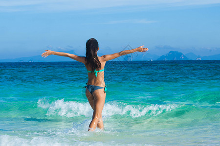 美丽的快乐女孩抱着双臂走向热带海洋快乐的女孩走向大海图片