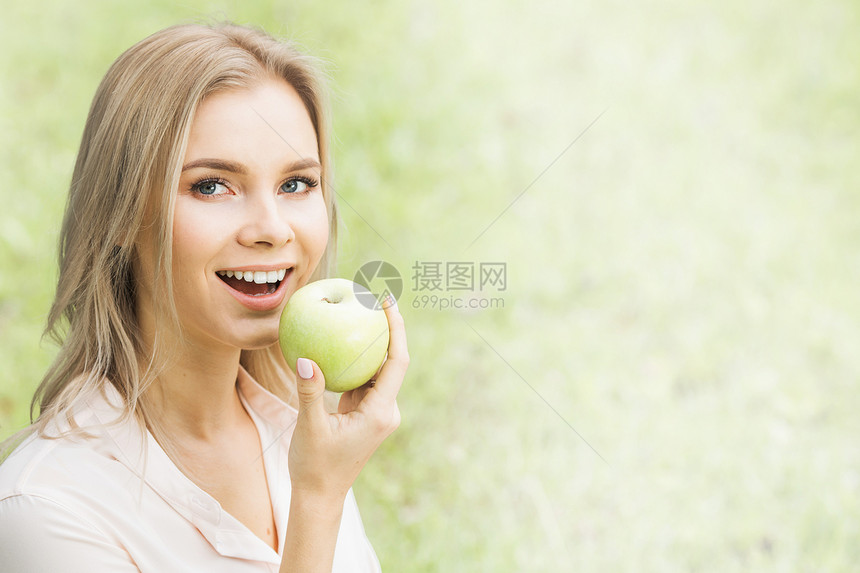 年轻的女人春天的草地背景上着新鲜的绿色苹果有绿苹果的女人图片