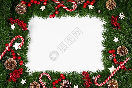 白纸糖果边框圣诞边框的树枝围绕白色背景与隔离,红色装饰,浆果,星星,锥,糖果罐头圣诞树树枝的圣诞框架背景