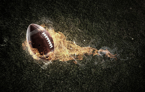 足球和火焰橄榄球黑暗背景下的火焰中美国足球比赛的背景