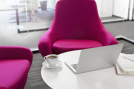 笔记本电脑与咖啡杯文件桌子上的粉红色椅子办公室图片