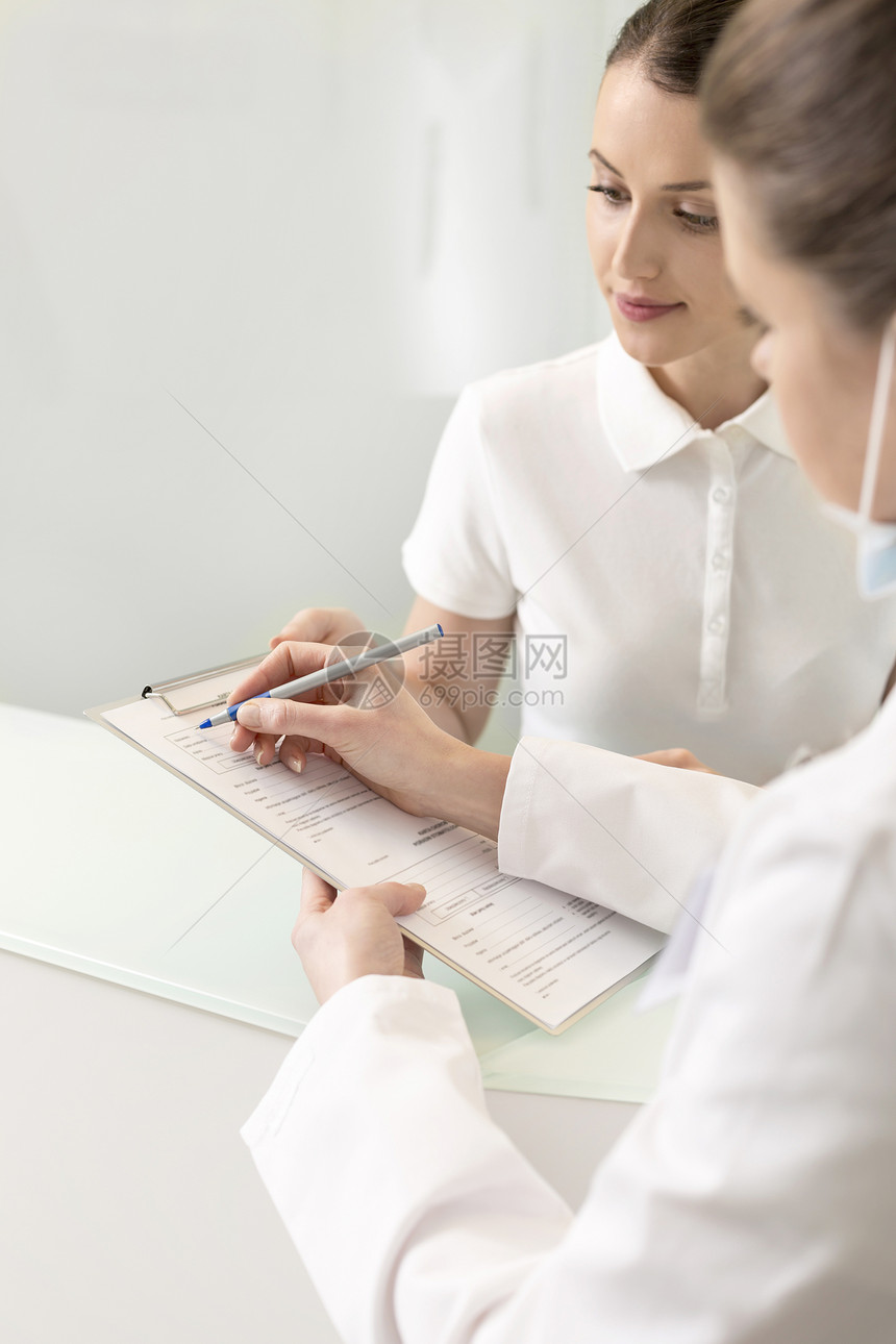 医生填写表格,同时与助理结帐柜台诊所讨论图片