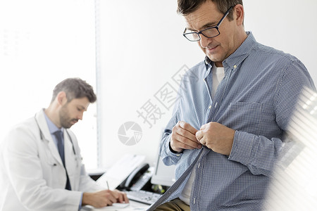病人脱衣服检查,而医生医院阅读医疗报告图片