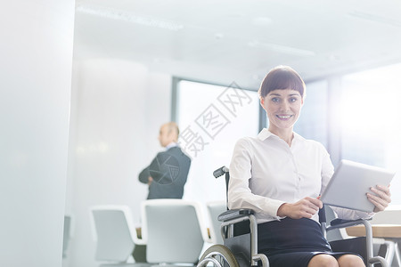 微笑的残疾女商人坐办公室的会议室里用数字平板电脑图片