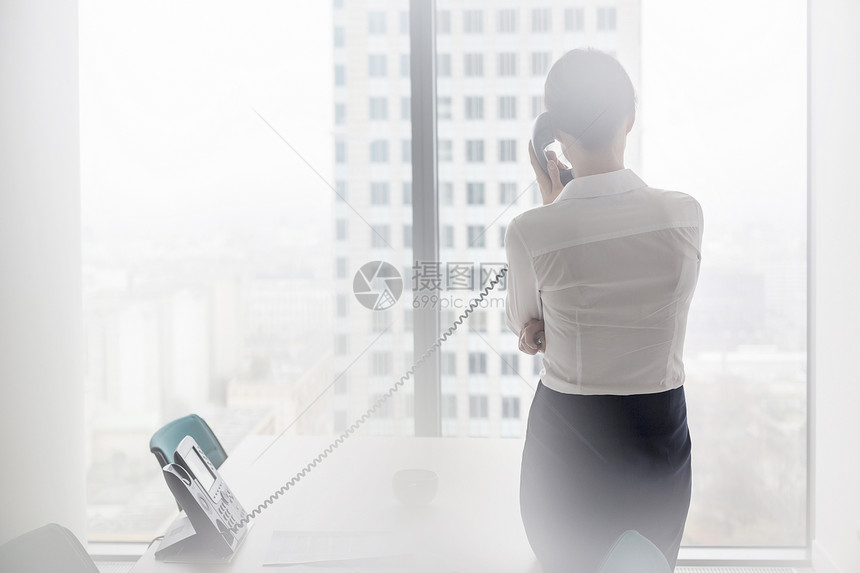 站办公室时,女商人座机电话上交谈的后视镜图片