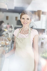 微笑美丽的年轻女服务员站餐厅柜台旁的肖像图片
