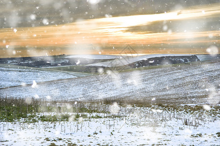 冬天的雪景田野上,大雪纷飞的暴风雨中,晚霞闪烁背景图片