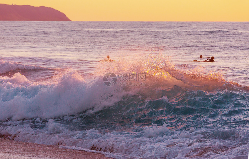 神奇的夏威夷海滩日落或日出时与冲浪者起海洋中波动波浪与温暖的日落颜色美国瓦胡海滩图片