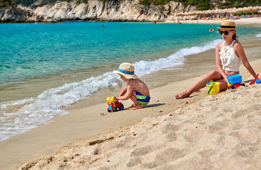 两岁的蹒跚学步的男孩海滩上妈妈玩海滩玩具暑假家庭假期希腊西索尼亚图片