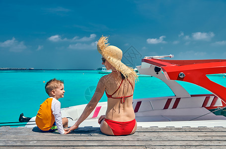 船头上男孩三岁的蹒跚学步的男孩母亲坐木船码头上马尔代夫的暑假家庭假期背景