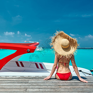 红色快艇穿着红色比基尼的女人坐木船码头上马尔代夫的暑假背景