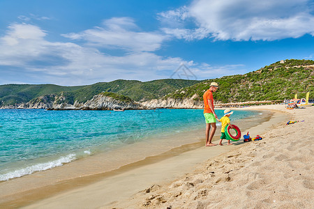 两岁的蹒跚学步的男孩父亲海滩上散步,着充气戒指暑假家庭假期希腊西索尼亚图片
