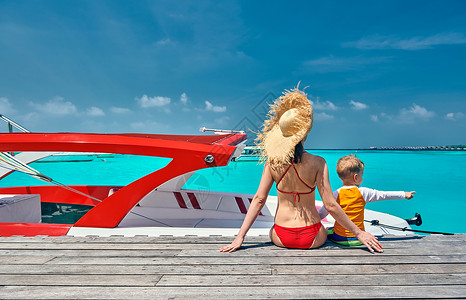 船头上男孩三岁的蹒跚学步的男孩母亲坐木船码头上马尔代夫的暑假家庭假期背景