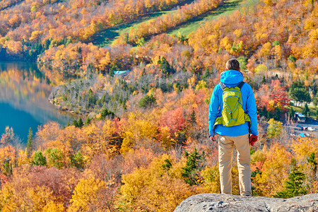 背包客男子徒步旅行艺术家的虚张声势秋天回声湖的景色法国公园的秋天颜色美国新罕布什尔州白山森林背景图片