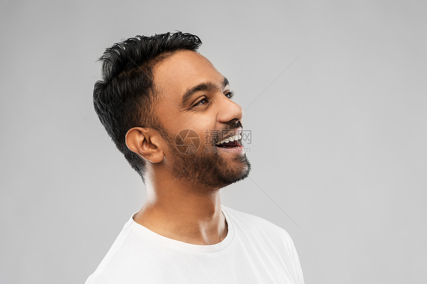情感,表达人的轻的笑印度男子灰色背景灰色背景上轻的笑着的印度男人图片