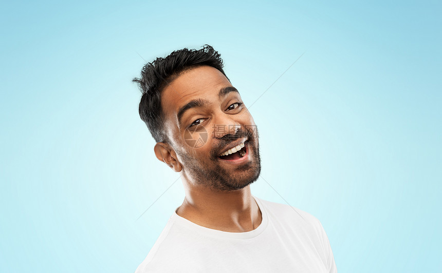 情感,表达人的轻的笑印度男子蓝色背景轻的笑着的印度男子蓝色背景图片
