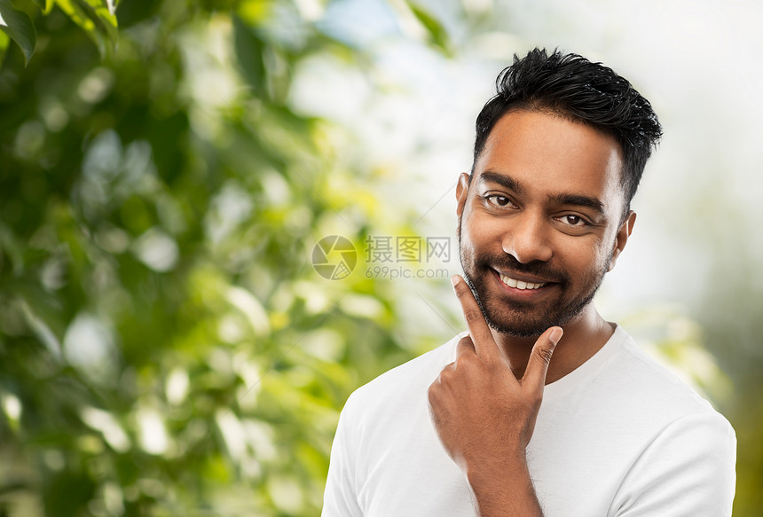 修饰人的微笑的印度男子触摸他的胡子绿色的自然背景微笑的印度男人抚摸他的胡子图片