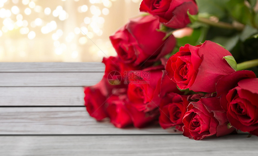 花,情人节假日红色玫瑰木板上的节日灯背景红玫瑰图片