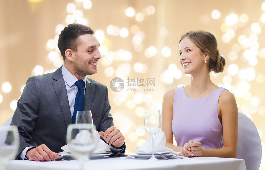 人,约会浪漫的幸福的夫妇餐厅用米色背景与节日灯交谈幸福的夫妇餐厅的节日灯图片