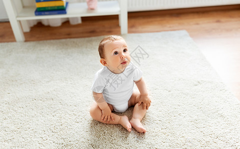 小婴儿坐家里的地板上仰望背景图片