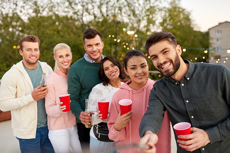 休闲人们的快乐的朋友与饮料自拍屋顶聚会夏天饮料的朋友屋顶派上自拍图片