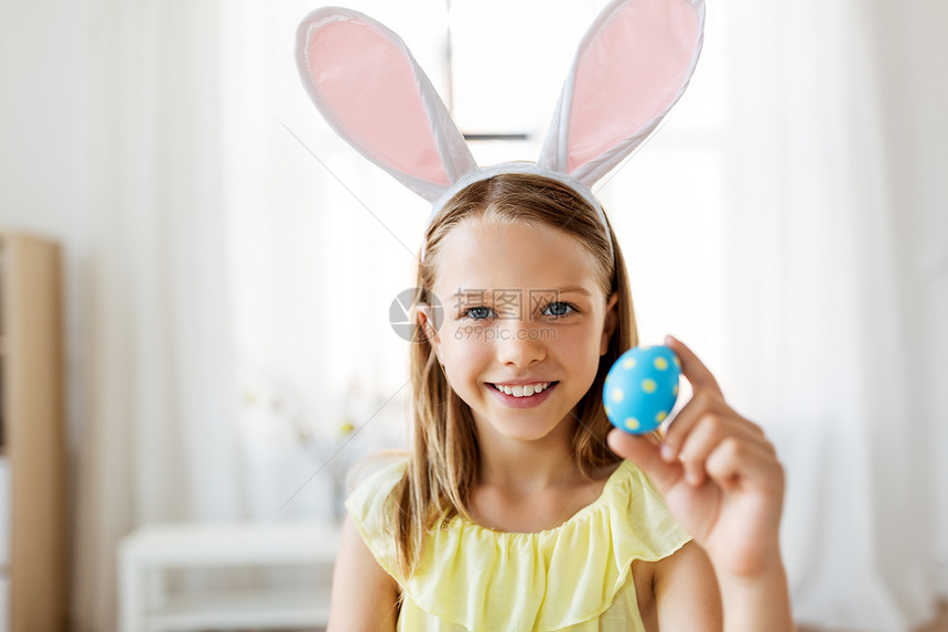 复活节,假日人们的快乐的女孩戴着兔子耳朵,头带着彩色鸡蛋家里家里彩色复活节彩蛋的快乐女孩图片