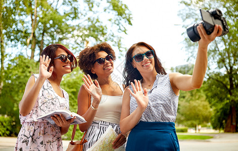 虚拟测井旅游,旅游技术快乐的女与城市指南记录视频博客夏季公园相机挥手旅行录制视频博客的女背景
