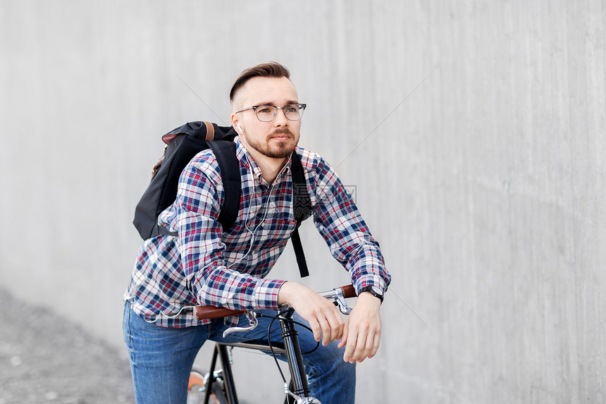 旅行,旅游生活方式轻的时尚男子戴着耳机,固定装备自行车背包城市街道带固定装备自行车背包的时髦男人图片