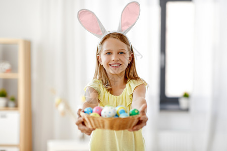 孩子拿着鸡蛋复活节,假日人们的快乐的女孩戴着兔子耳朵,头带着篮子彩色鸡蛋家里家里彩色复活节彩蛋的快乐女孩背景