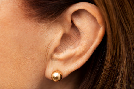 金色女人健康,人听力老妇女耳朵与黄金耳环用金色耳环把高级女人的耳朵合上背景