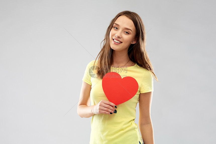 情人节人们的微笑的轻女人十几岁的女孩穿着黄色T恤,红色的心灰色的背景带着红心微笑的十几岁女孩图片