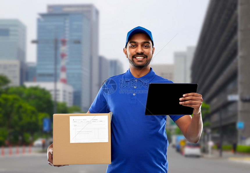 邮件服务,技术装运快乐的印度送货人与包裹盒平板电脑蓝色制服托基奥城市背景印度送货人带平板电脑包裹盒图片