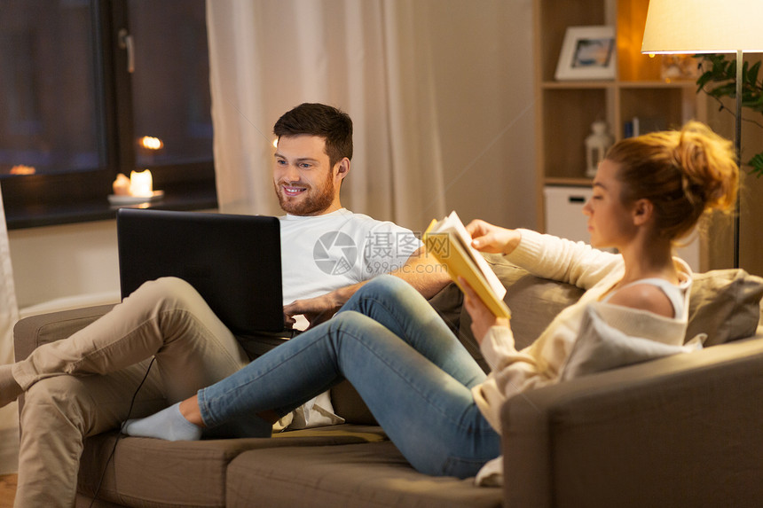 休闲人们的快乐的夫妇与笔记本电脑书籍家里晚上家里笔记本电脑书图片