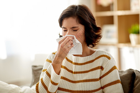 急性鼻炎流鼻涕生病的女人家里用纸巾擦鼻子背景