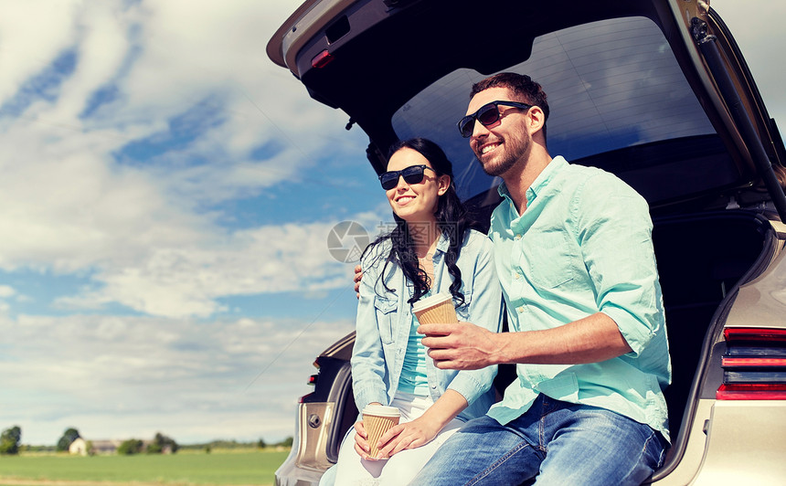旅行,暑假,公路旅行,休闲人们的快乐的夫妇喝咖啡次杯子坐后备箱的掀背车户外幸福的情侣掀背车后备箱里喝咖啡图片