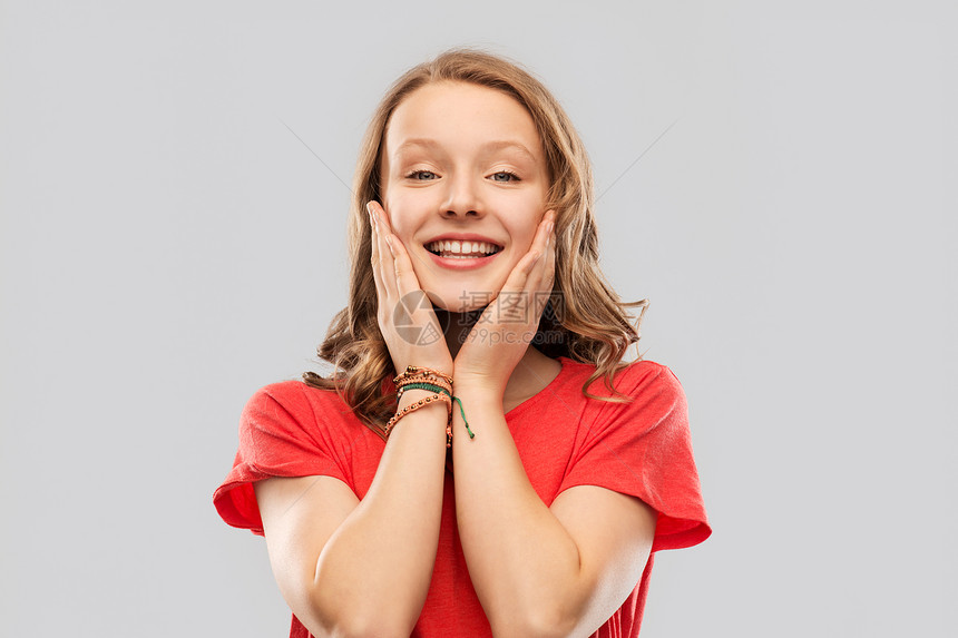 情感,表情人的快乐微笑的十几岁女孩,长发红色T恤灰色背景微笑的十几岁女孩穿着红色T恤,灰色图片