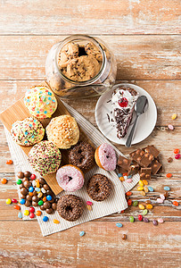 糖果食品釉甜甜圈,巧克力,滴糖,燕麦饼干块蛋糕木桌上桌子上同的糖果图片