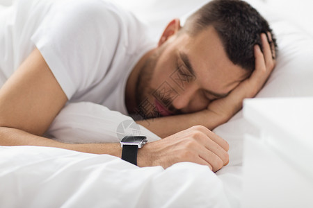人,技术休息的近距离的人与智能手表睡床上用智能手表床上睡觉的男人图片